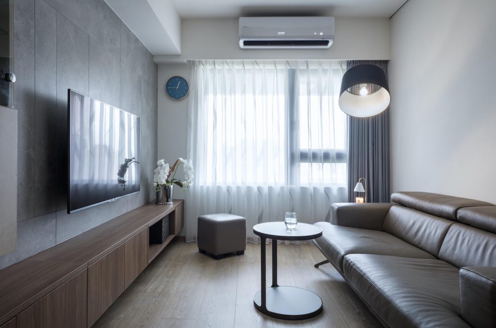 客廳採光明亮，電視牆搭配深色下端型收納櫃，延伸視覺、拉寬縱身尺度。